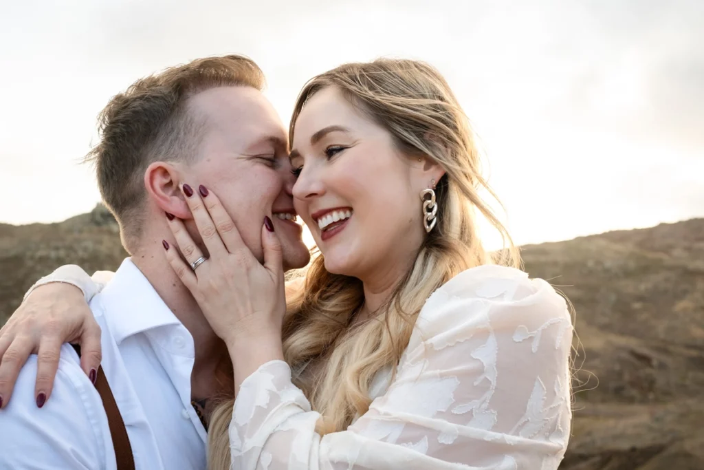 Close-up joyful couple laughing and sharing an intimate moment, with a soft natural backdrop