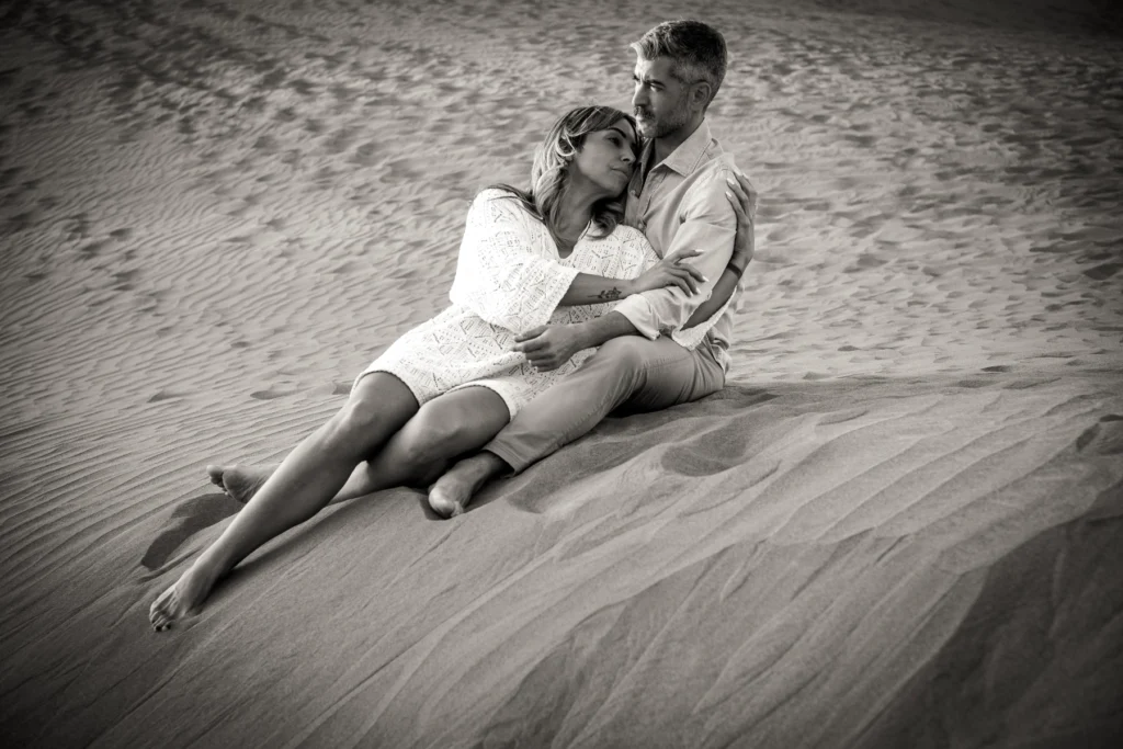 A couple stands together on the sand dunes, embracing in an intimate and romantic moment during their elopement.