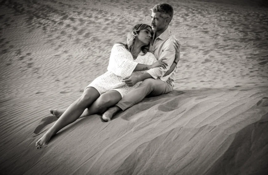 A couple stands together on the sand dunes, embracing in an intimate and romantic moment during their elopement.